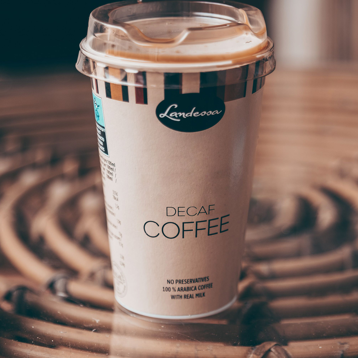 A disposable coffee cup with a clear plastic lid, labeled 'DECAF COFFEE' and a black Landessa logo on the front